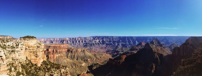 Panoramic view of rock formations against blue sky