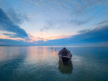 Boat in sea against sky during sunset