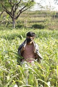 Young man wearing mask looking away while standing in farm