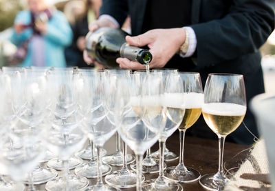 Midsection of man pouring wine in glasses on table