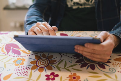 Midsection of man using mobile phone while sitting on table