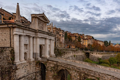 Low angle view of old building against cloudy sky, porta san giacomo in bergamo