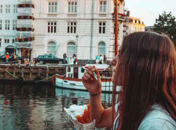 Full length portrait of woman with mobile phone in canal