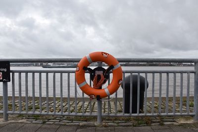 Man standing by railing by sea against sky