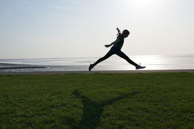 Full length of man jumping at beach against sky