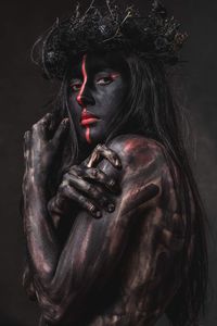 Portrait of woman with body paint against black background