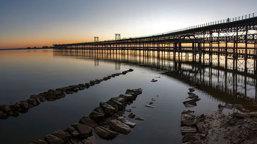 Bridge over river against sky during sunset