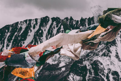 Midsection of man holding umbrella on mountain against sky