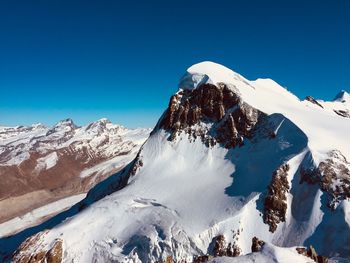 Scenic view of snowcapped mountains against clear blue sky