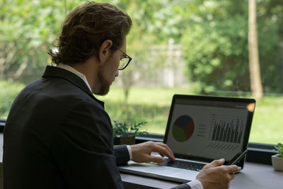 Businessman using laptop and phone at desk in office