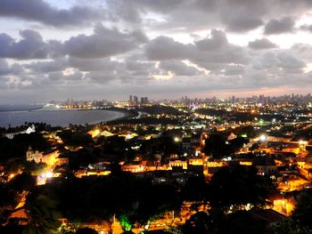 Illuminated cityscape against cloudy sky