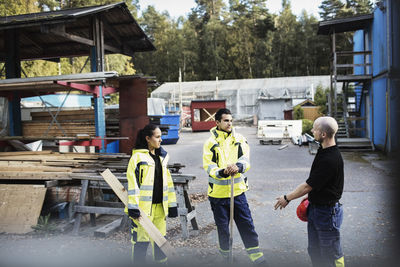 Teacher talking to carpentry students outside school