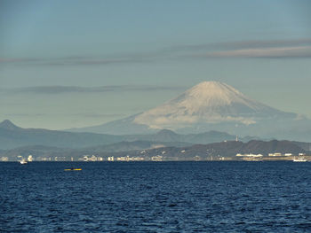 Scenic view of sea by mountains against sky