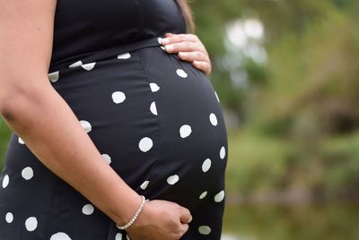 Midsection of pregnant woman touching her belly