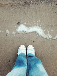 Low section of man standing on sand