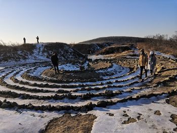 People walking on land against clear sky