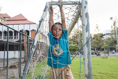 Portrait of boy hanging on fence