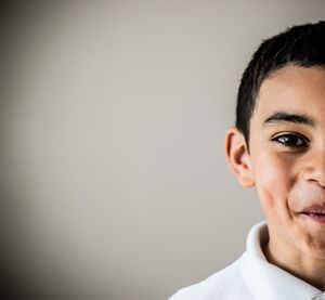 Portrait of boy face in half over gray background