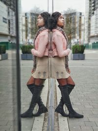 Full length of woman leaning on glass wall