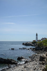 Lighthouse by sea against sky