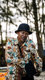 Man wearing hat standing against tree