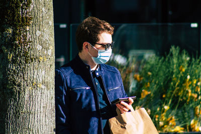 Young man using mobile phone while standing on laptop