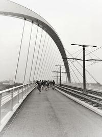 People walking on bridge against clear sky