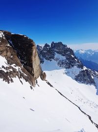 Scenic view of snowcapped mountains against clear blue sky