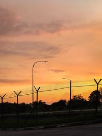 Silhouette street against sky during sunset