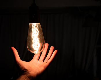 Close-up of hand holding illuminated light bulb