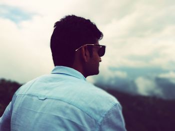 Man wearing sunglasses standing against sky