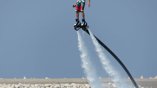 Low section of person flyboarding against clear sky