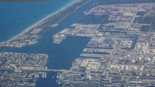 Aerial view of city by sea against sky