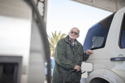 Elderly man fueling car at gas station