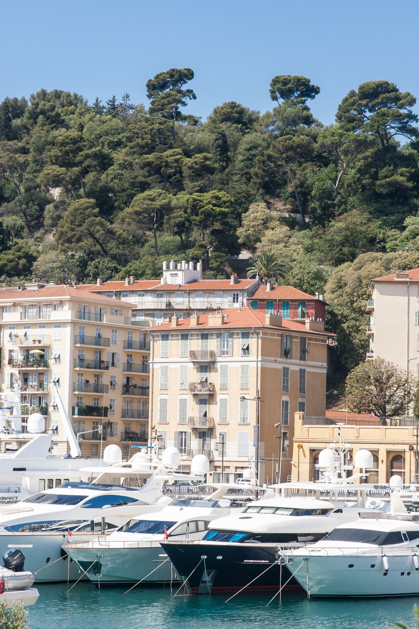 BOATS MOORED IN HARBOR AGAINST BUILDINGS