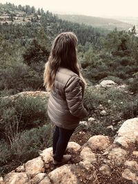 Rear view of woman standing on rock