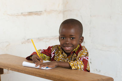 Portrait of smiling boy holding table