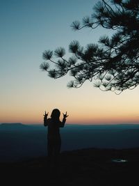 Rear view of silhouette person standing on land against sky during sunset