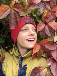 A boy in a pink hat stands on a background red autumn leaves of wild grapes and a smile 