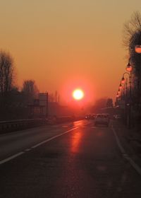 Cars on road against sky during sunset