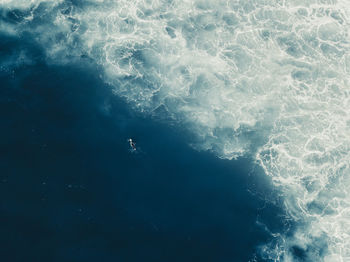 Aerial view of a surfer paddling in the ocean