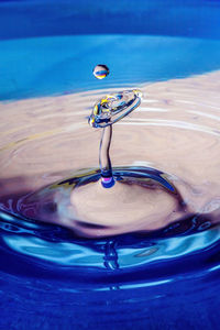 Close-up of drop falling on blue water