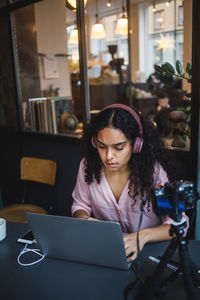 Young woman using phone while sitting on table