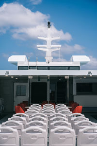 Chairs and tables by building against sky