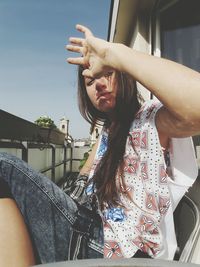 Girl sitting on chair while shielding eyes