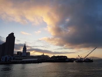 River in front of buildings against cloudy sky