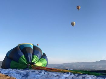 Men with hot air balloon on mountain against clear sky