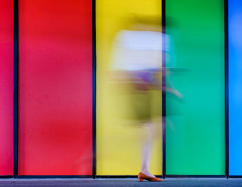 Low section of woman walking on multi colored wall