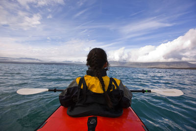 Woman rowing sea kayak on jökulsárlón glacier lagoon in iceland