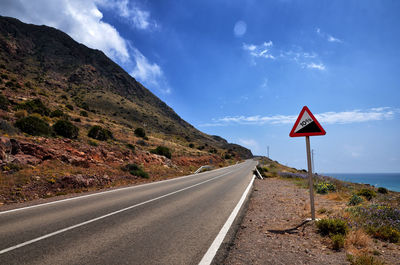 Road sign by mountains against sky